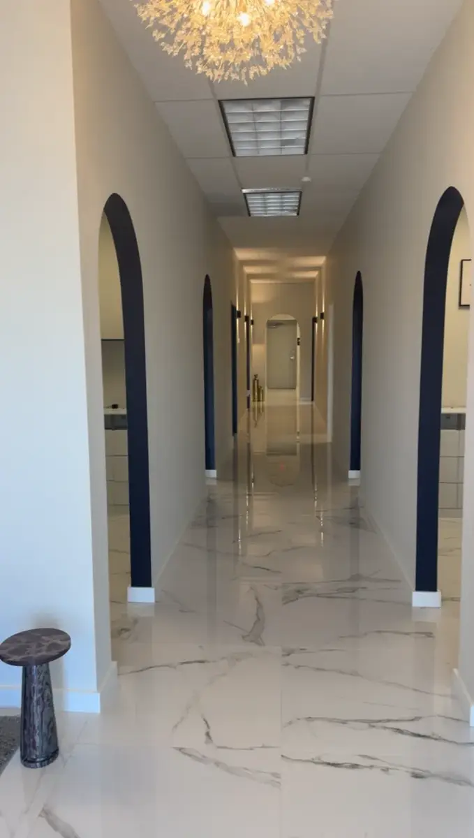 Finished commercial hallway with arched doorways and marble-look tile